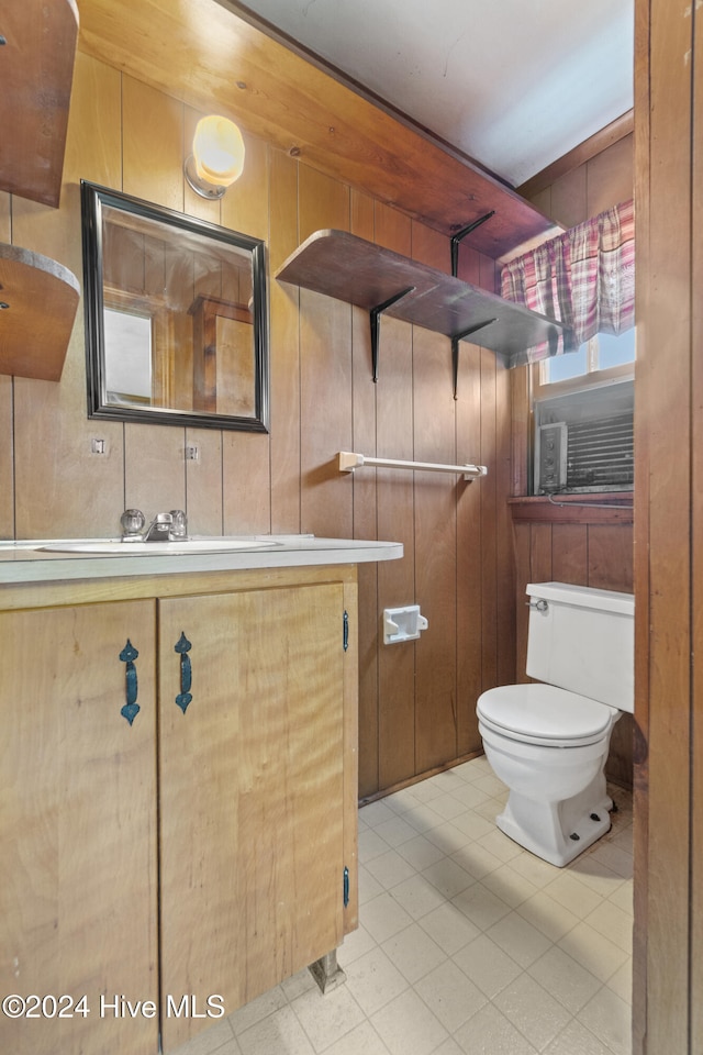 bathroom featuring tile patterned floors, wooden walls, vanity, and toilet