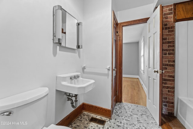 bathroom with a bathing tub, sink, wood-type flooring, and toilet