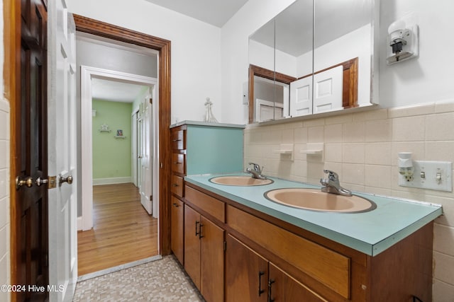 bathroom with vanity, hardwood / wood-style flooring, and tasteful backsplash