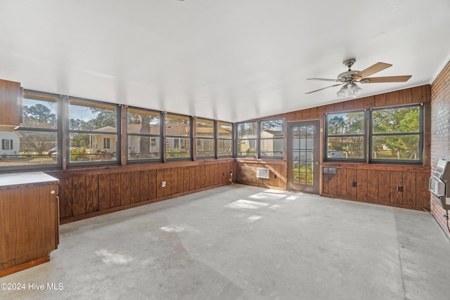 unfurnished sunroom with a wall unit AC, ceiling fan, a healthy amount of sunlight, and vaulted ceiling