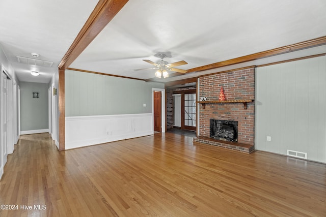 unfurnished living room with hardwood / wood-style floors, ceiling fan, ornamental molding, and a fireplace