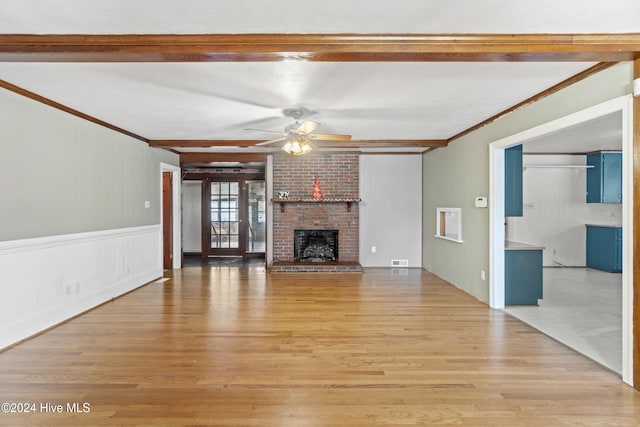 unfurnished living room with ceiling fan, a fireplace, crown molding, and light wood-type flooring