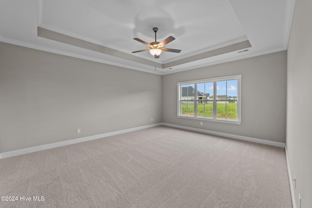 carpeted empty room featuring a tray ceiling, ceiling fan, and ornamental molding