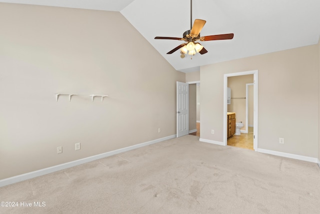 unfurnished bedroom with light carpet, a walk in closet, ensuite bath, ceiling fan, and high vaulted ceiling