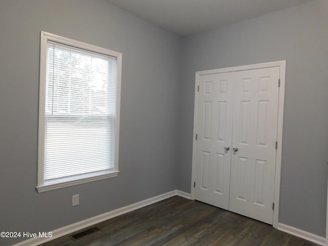 unfurnished bedroom with dark hardwood / wood-style floors and a closet