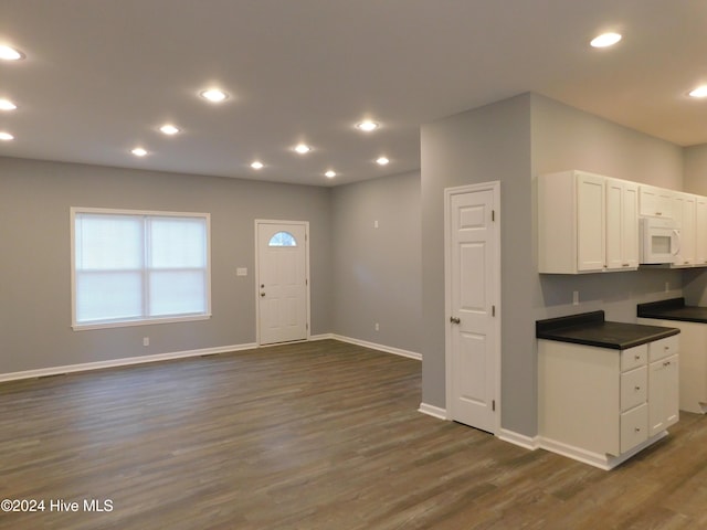 12521 Mckinnon Dr, Laurinburg, NC 28352 - kitchen with white microwave, dark countertops, dark wood-style flooring, white cabinetry, and recessed lighting