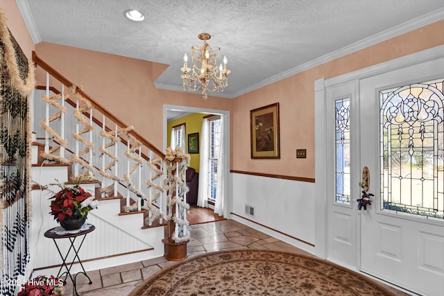 foyer with a chandelier, wood-type flooring, a textured ceiling, and crown molding