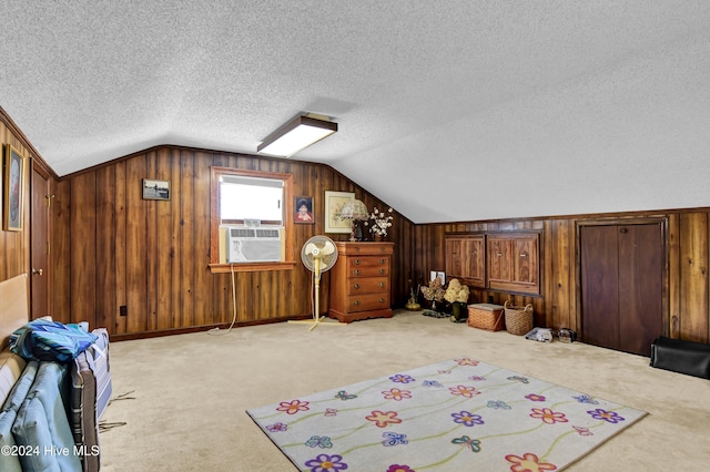 additional living space featuring cooling unit, light colored carpet, vaulted ceiling, a textured ceiling, and wooden walls