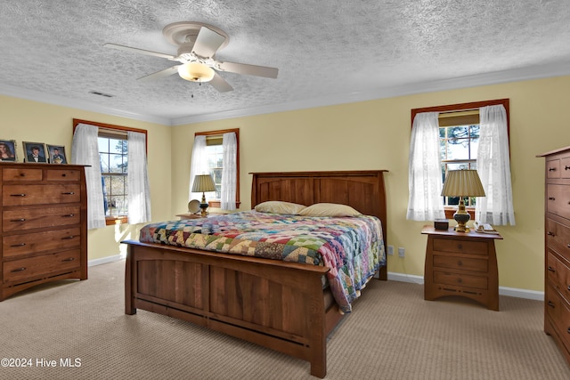 bedroom with ceiling fan, crown molding, light colored carpet, and a textured ceiling