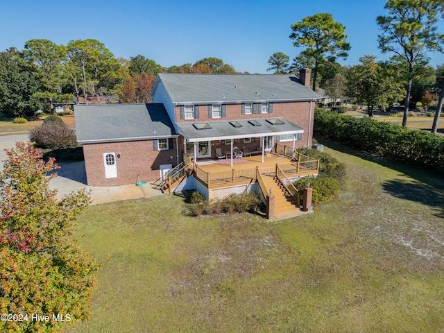 rear view of house featuring a lawn and a wooden deck