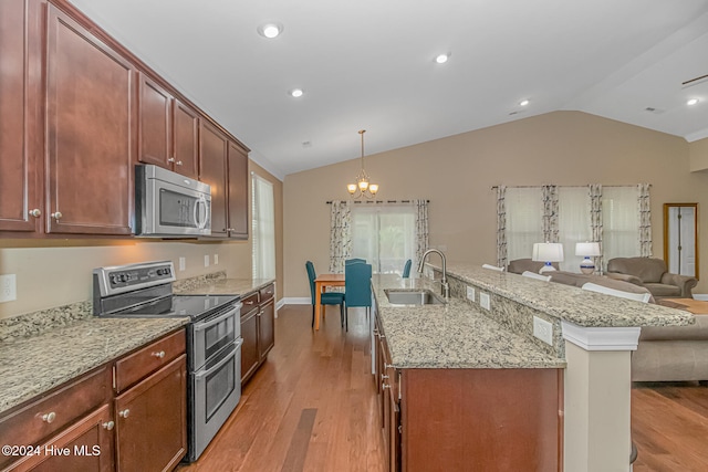 kitchen featuring pendant lighting, lofted ceiling, sink, light wood-type flooring, and appliances with stainless steel finishes