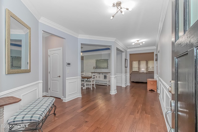 hall featuring ornate columns, crown molding, an inviting chandelier, and hardwood / wood-style flooring