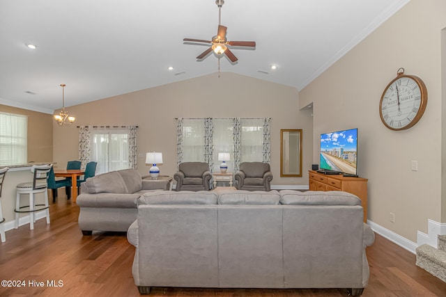 living room with hardwood / wood-style flooring, ceiling fan with notable chandelier, ornamental molding, and vaulted ceiling