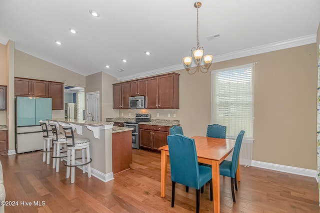 kitchen with a center island with sink, pendant lighting, stainless steel appliances, and light hardwood / wood-style flooring