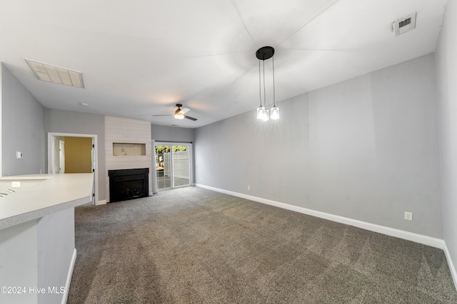 unfurnished living room featuring ceiling fan, a fireplace, and dark colored carpet