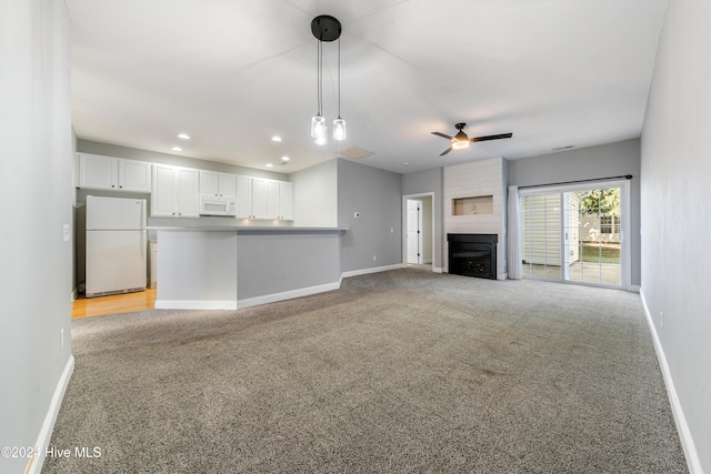 unfurnished living room featuring a large fireplace, light colored carpet, and ceiling fan