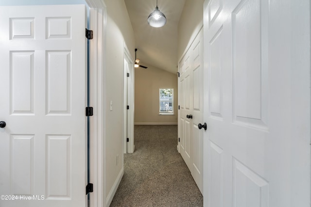 hall with dark carpet and lofted ceiling