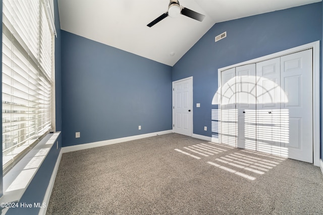 carpeted empty room featuring vaulted ceiling, ceiling fan, and a healthy amount of sunlight