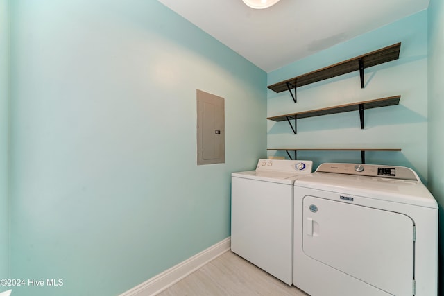 washroom with light wood-type flooring, separate washer and dryer, and electric panel