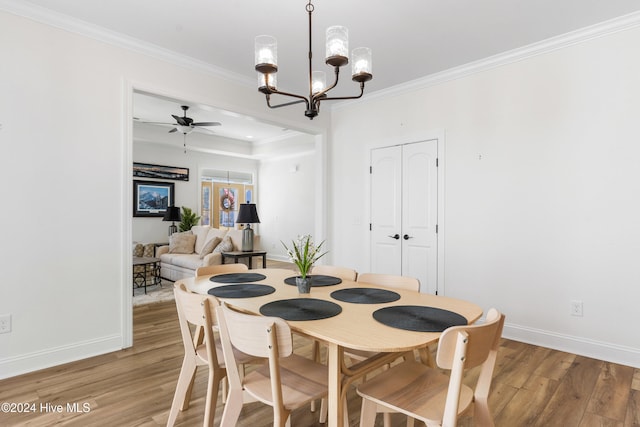 dining space with ceiling fan with notable chandelier, light wood-type flooring, and ornamental molding