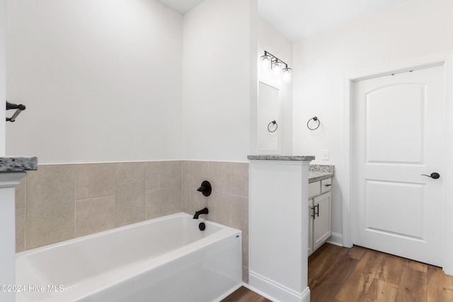 bathroom with hardwood / wood-style floors, vanity, and a tub