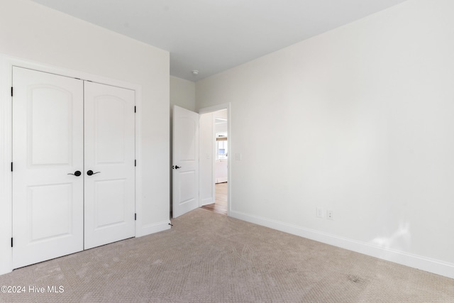 unfurnished bedroom with light colored carpet and a closet