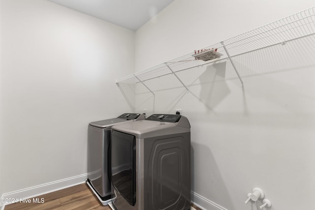 laundry area with wood-type flooring and washing machine and clothes dryer