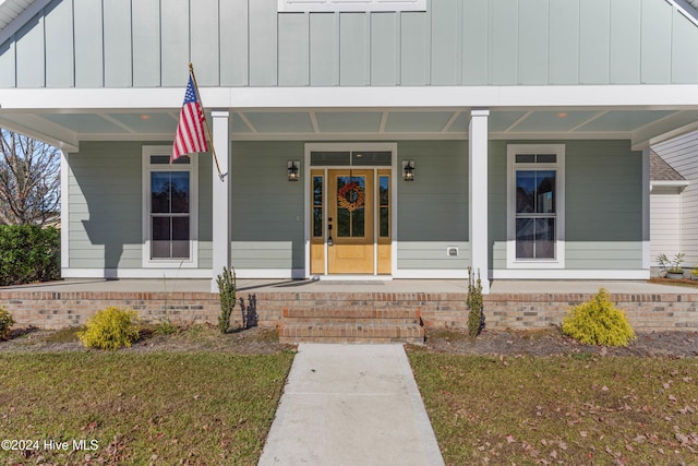 entrance to property featuring a yard and a porch