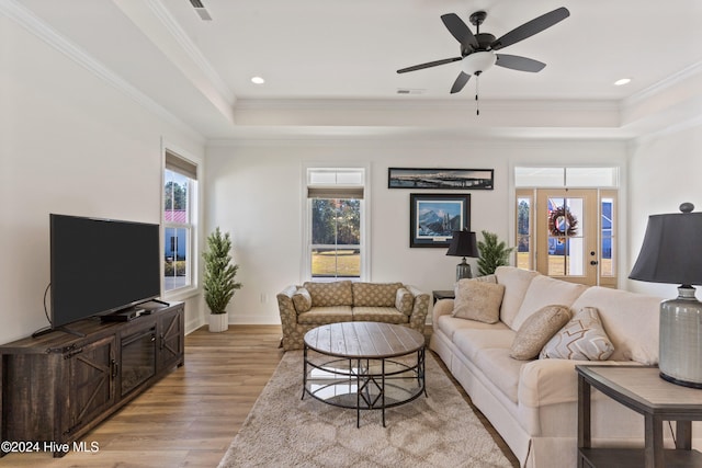 living room with crown molding, ceiling fan, and light wood-type flooring