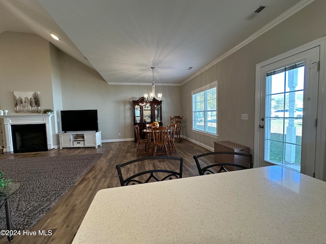 dining area featuring dark hardwood / wood-style floors, ornamental molding, a chandelier, and vaulted ceiling