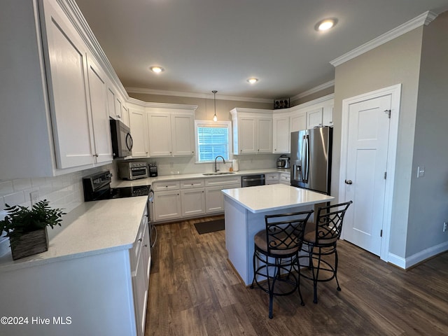 kitchen with appliances with stainless steel finishes, dark wood-type flooring, sink, pendant lighting, and a center island