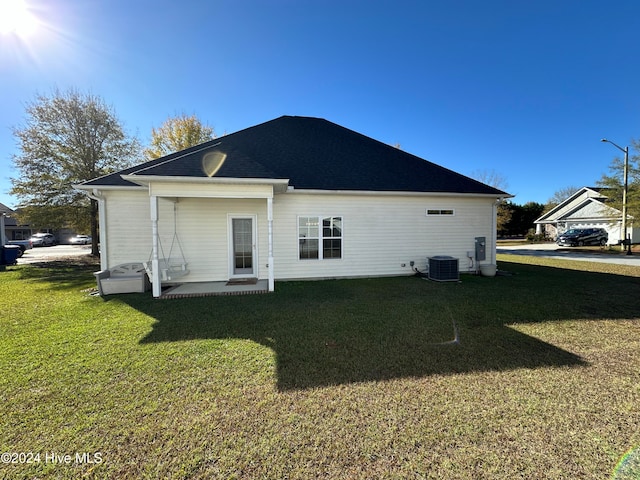 back of house featuring central air condition unit and a lawn