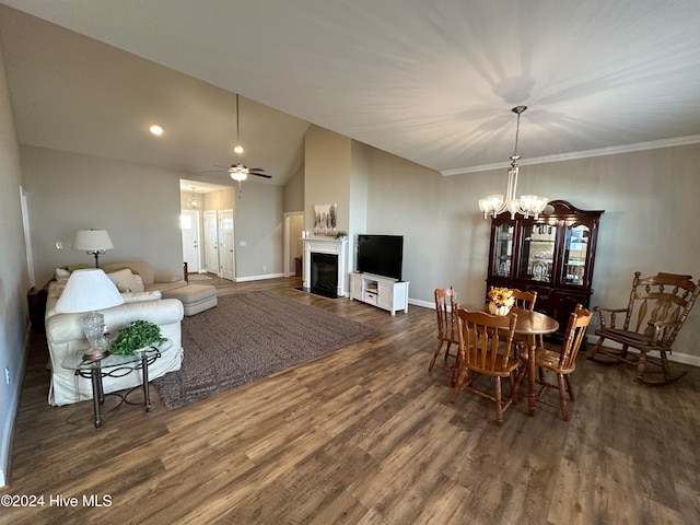 dining space with lofted ceiling, dark wood-type flooring, ceiling fan with notable chandelier, and ornamental molding