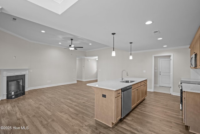 kitchen with a center island with sink, stainless steel appliances, sink, hardwood / wood-style floors, and pendant lighting