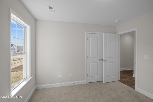 unfurnished bedroom with multiple windows, a closet, and carpet flooring