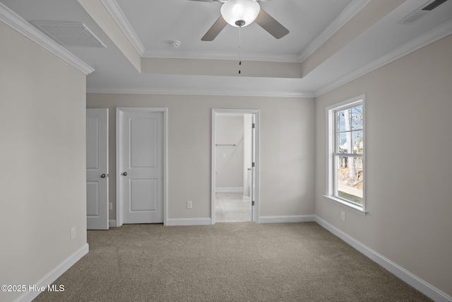 unfurnished bedroom featuring light carpet, crown molding, and a tray ceiling