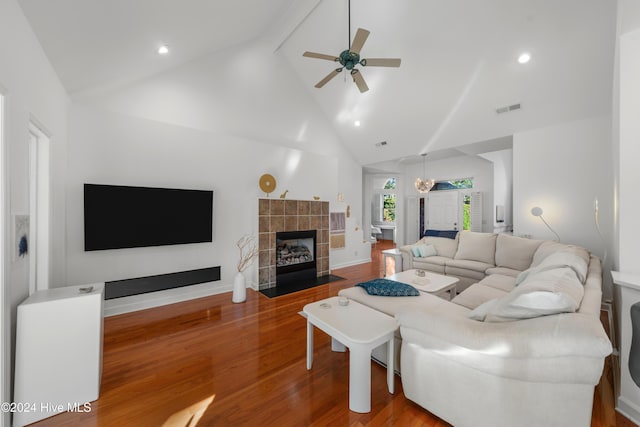 living room featuring a tile fireplace, high vaulted ceiling, ceiling fan with notable chandelier, beam ceiling, and wood-type flooring