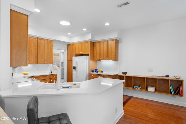 kitchen featuring kitchen peninsula, sink, white refrigerator with ice dispenser, and light wood-type flooring