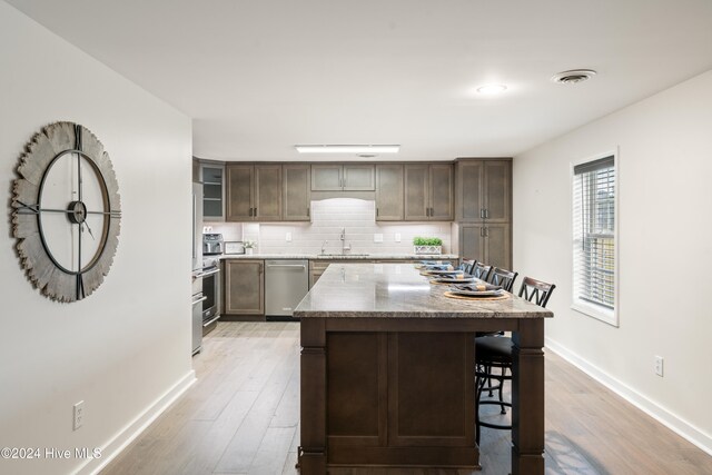 kitchen featuring appliances with stainless steel finishes, light wood-type flooring, a kitchen island, and sink