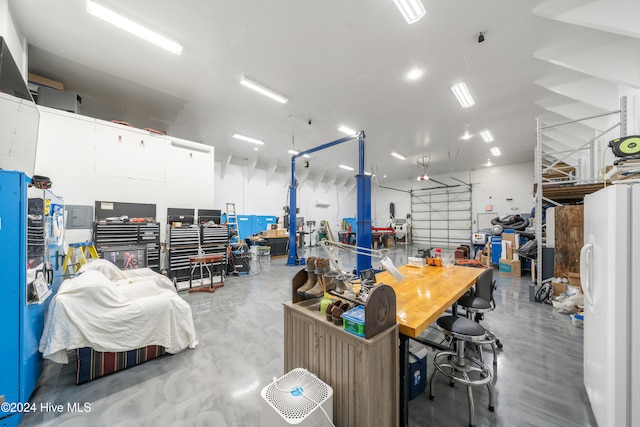 garage featuring a workshop area and white refrigerator with ice dispenser