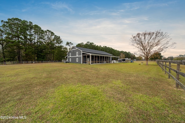 yard at dusk featuring an outbuilding and a rural view