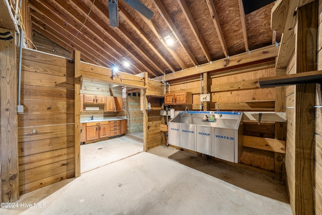 interior space with wood walls, ceiling fan, and lofted ceiling