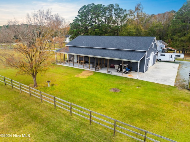 back of property featuring a rural view and a lawn