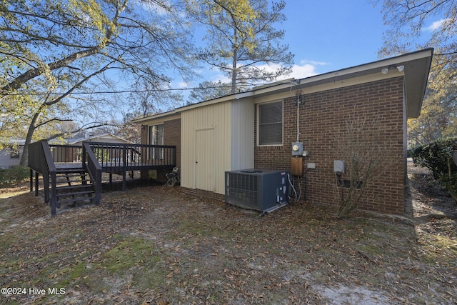 back of property with a wooden deck and central AC