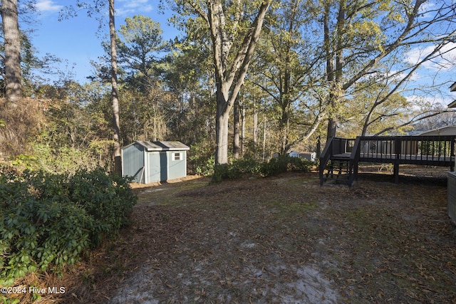 view of yard featuring a wooden deck and a storage unit