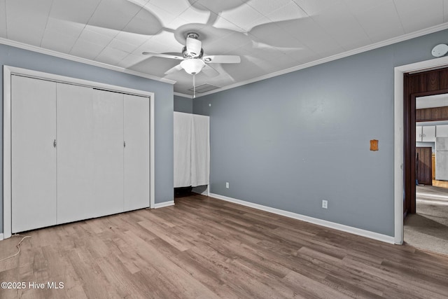 unfurnished bedroom featuring light wood-type flooring, a closet, ceiling fan, and crown molding