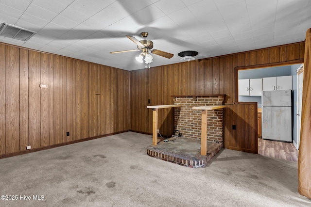 basement featuring light carpet, white refrigerator, and ceiling fan