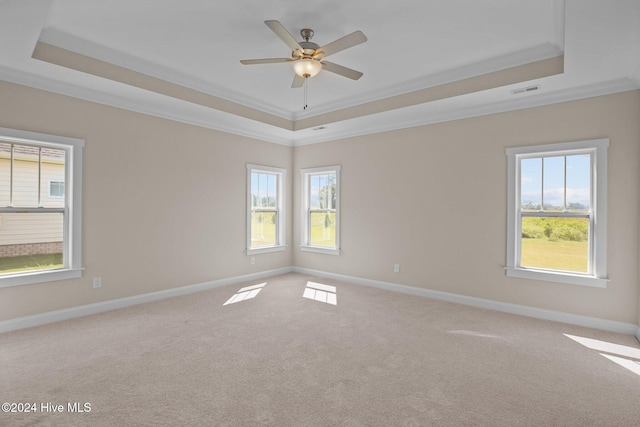 empty room featuring ceiling fan, light colored carpet, a tray ceiling, and ornamental molding