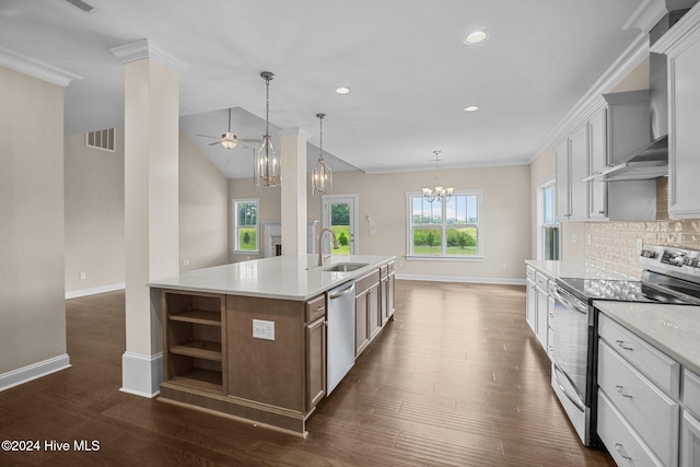 kitchen with ceiling fan with notable chandelier, stainless steel appliances, an island with sink, sink, and light stone counters