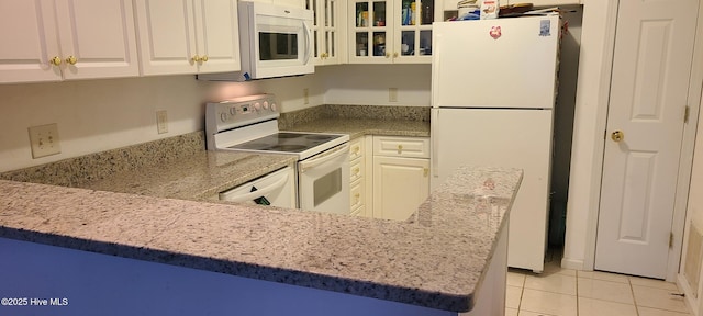 kitchen with light tile patterned floors, white appliances, white cabinetry, light stone counters, and kitchen peninsula